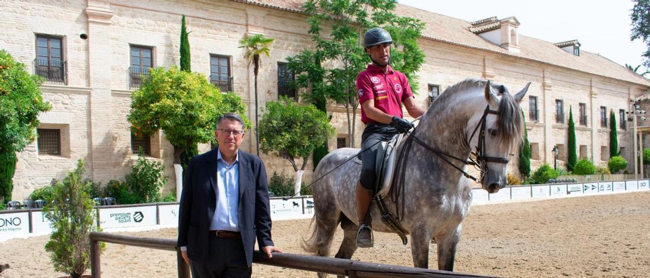 El presidente de Córdoba Ecuestre, Rafael Blanco, de pie, junto a un jinete y su caballo, en Caballerizas Reales.