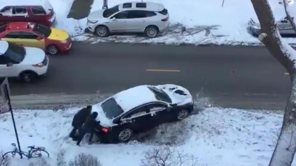 Dos personas empujan su vehículo en una calle de Chicago.