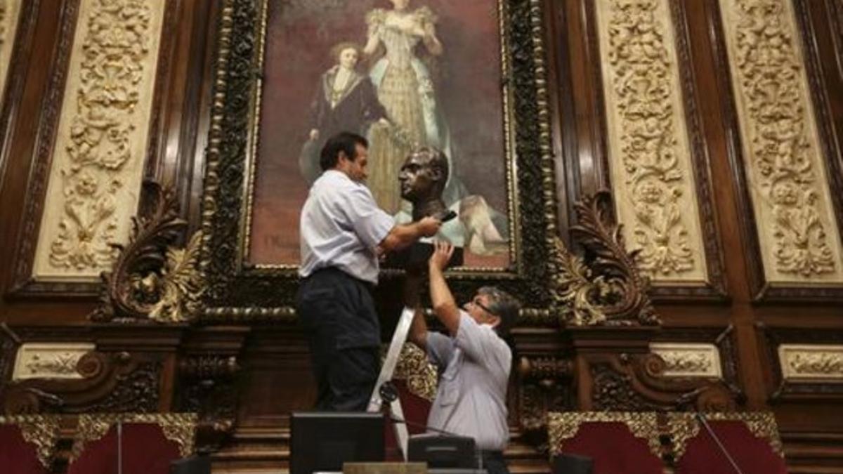 Dos trabajadores municipales retiran el busto del rey Juan Carlos I, en julio.