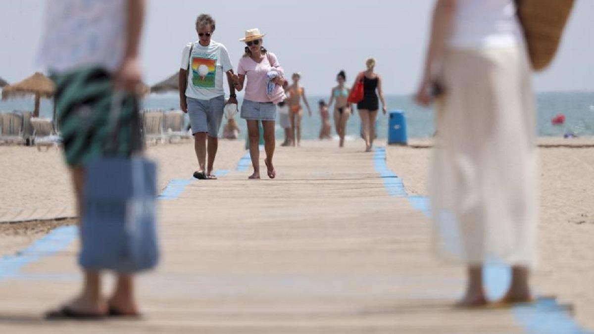 Imagen de varias personas caminando por una playa.