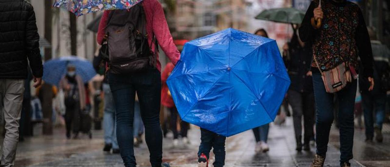 Un pequeño se resguarda de la lluvia con su paraguas azul