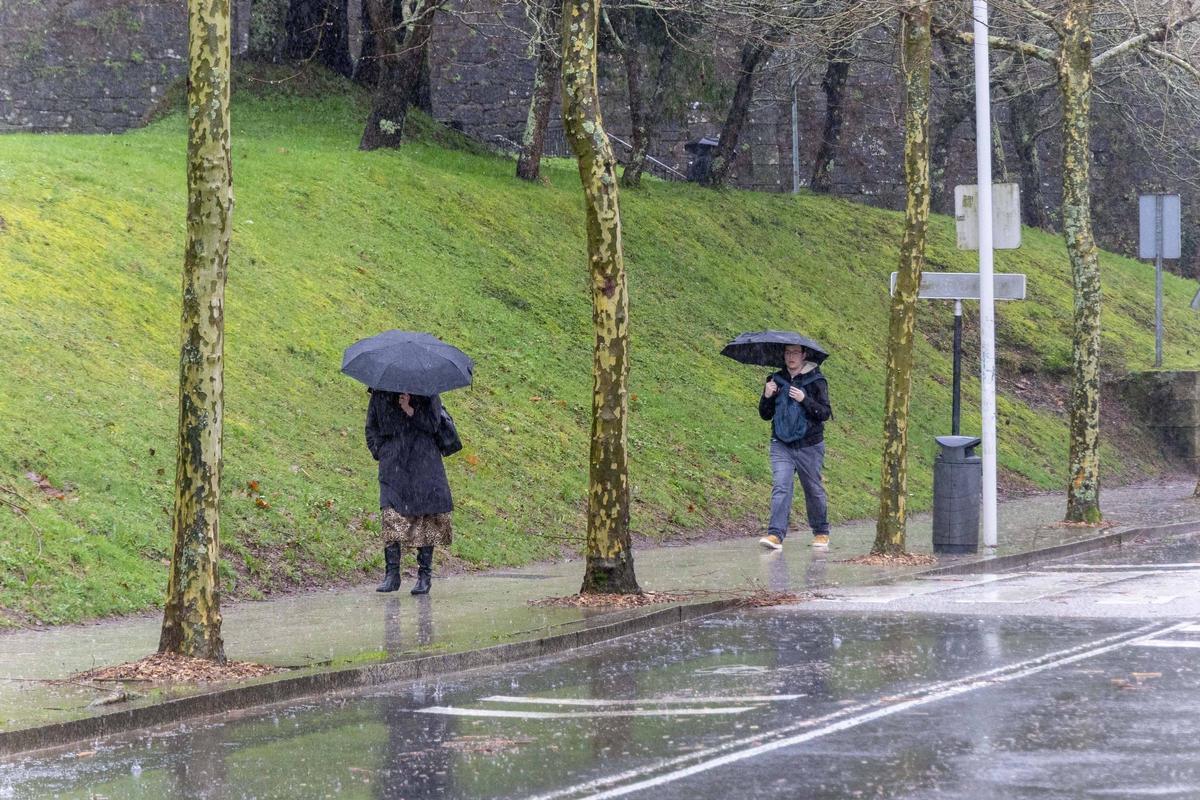 Dos santiagueses caminan por la acera en plena borrasca