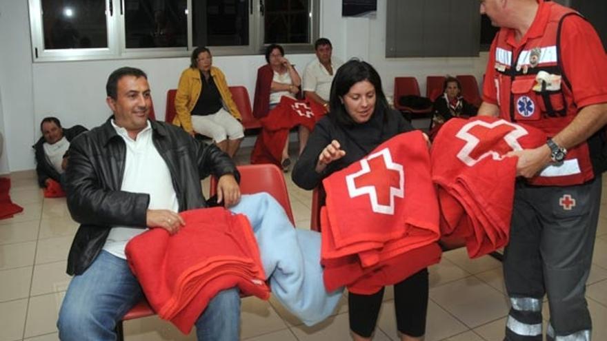 Voluntarios de Cruz Roja reparten mantas a los pasajeros en las oficinas de Transmediterránea.