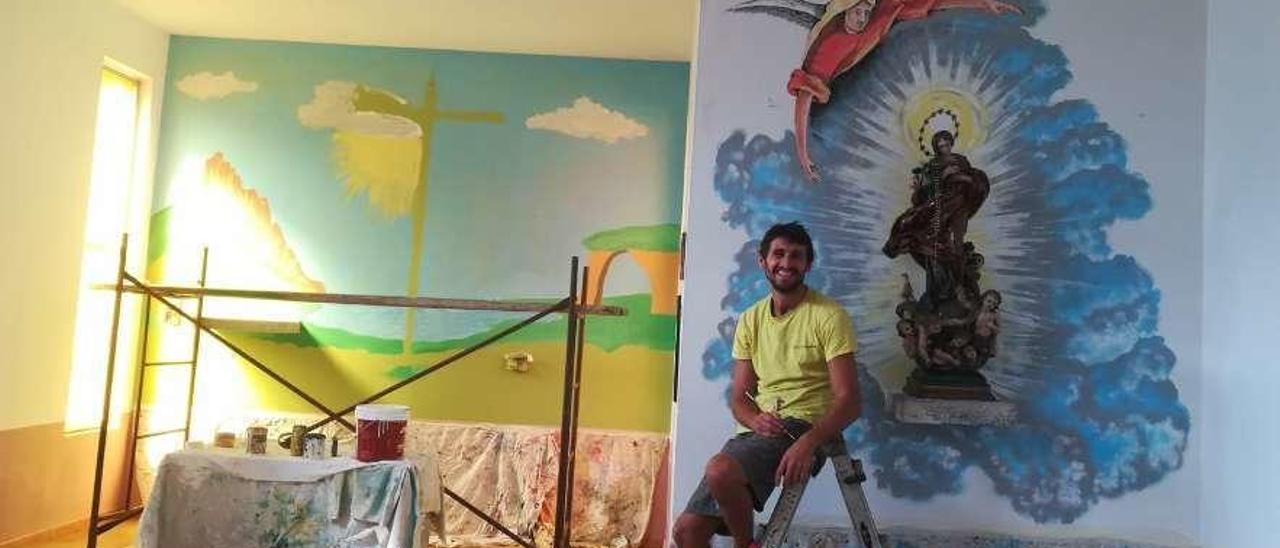 El artista Dan Miravalles, ante las paredes que decora en la iglesia parroquial de Sellañu, en Ponga.