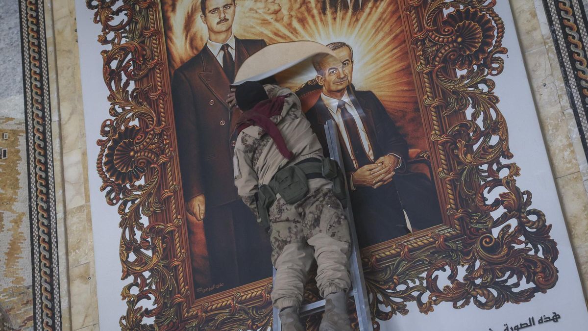 Un soldado rebelde rasga un retrato de Bashar el Asad y su padre, Hazef, en el aeropuerto internacional de Alepo.