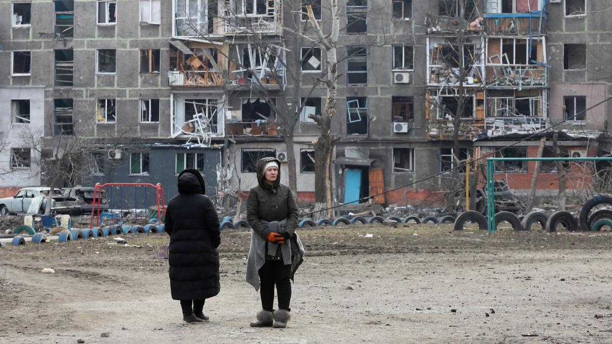 Dos mujeres frente a un edificio dañado por los bombardeos cerca de Mariúpol.