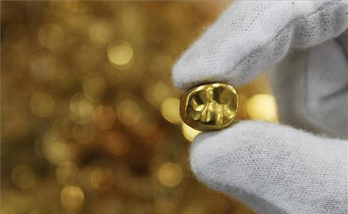 Un empleat mostra una dent d’or en un negoci de compravenda d’aquest material a Tòquio (Japó).