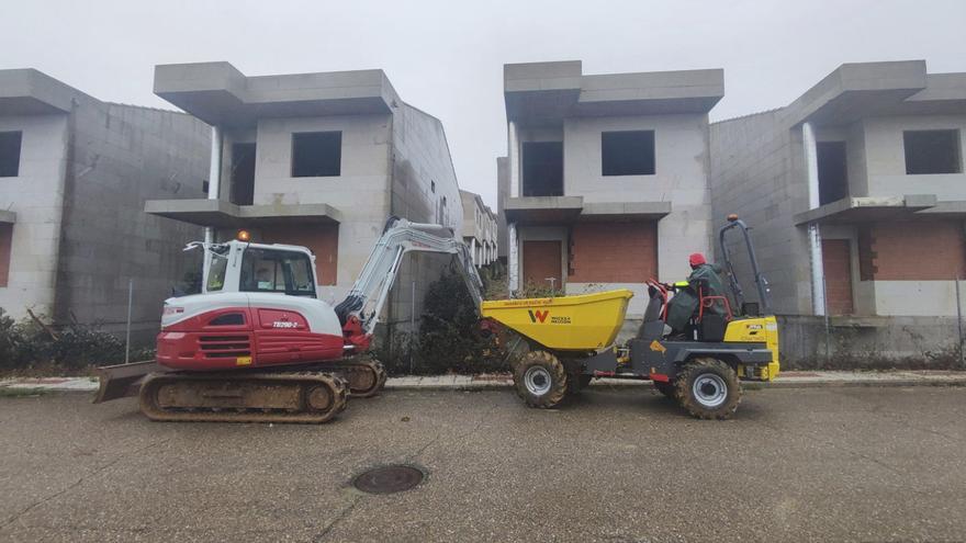 Operarios trabajando en la limpieza de vegetación en las viviendas unifamiliares inconclusas de Pola de Lena.