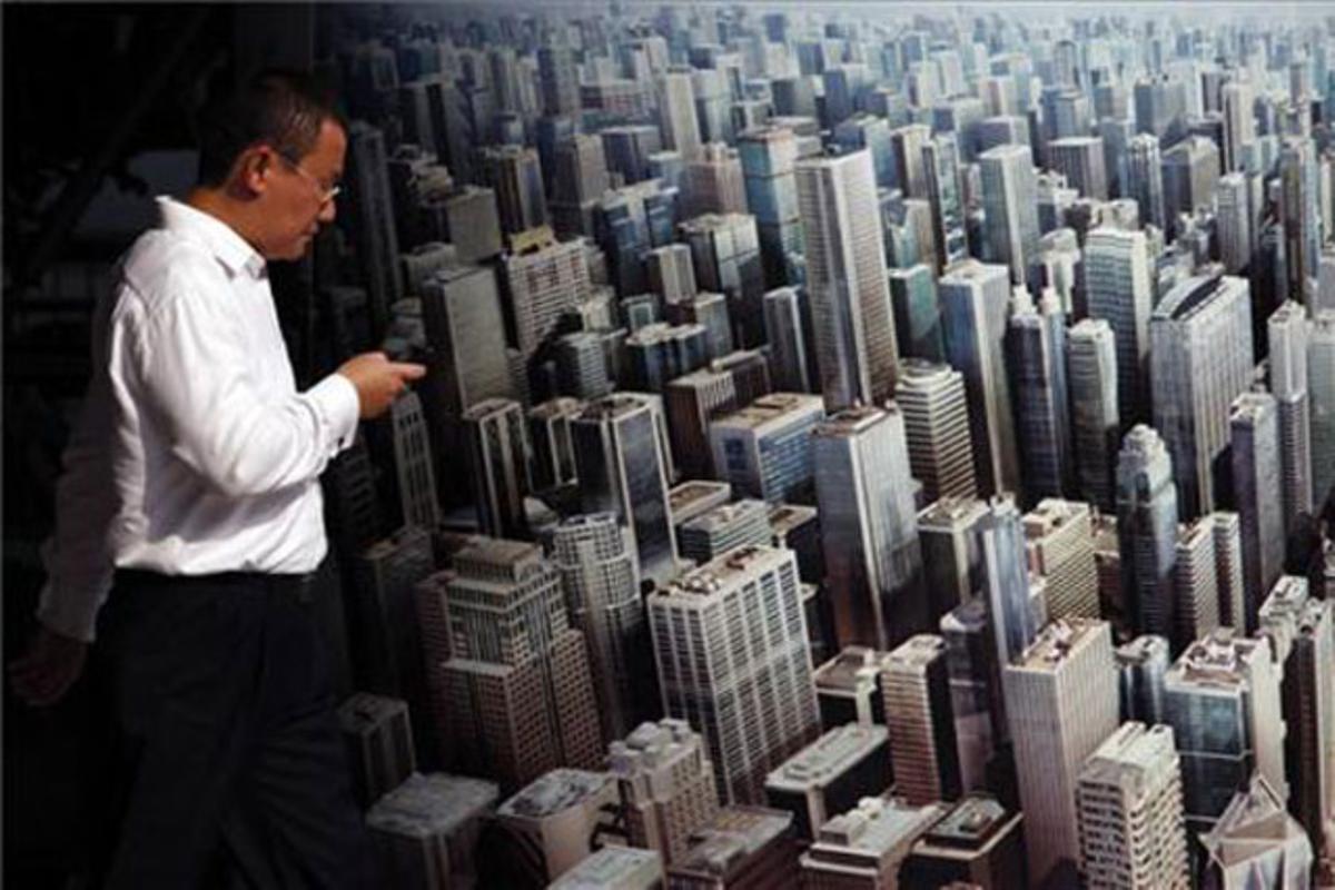 Un oficinista mira el seu telèfon mòbil mentre passa per davant d’un anunci publicitari fora de la seu de l’HSBC a Hong Kong.