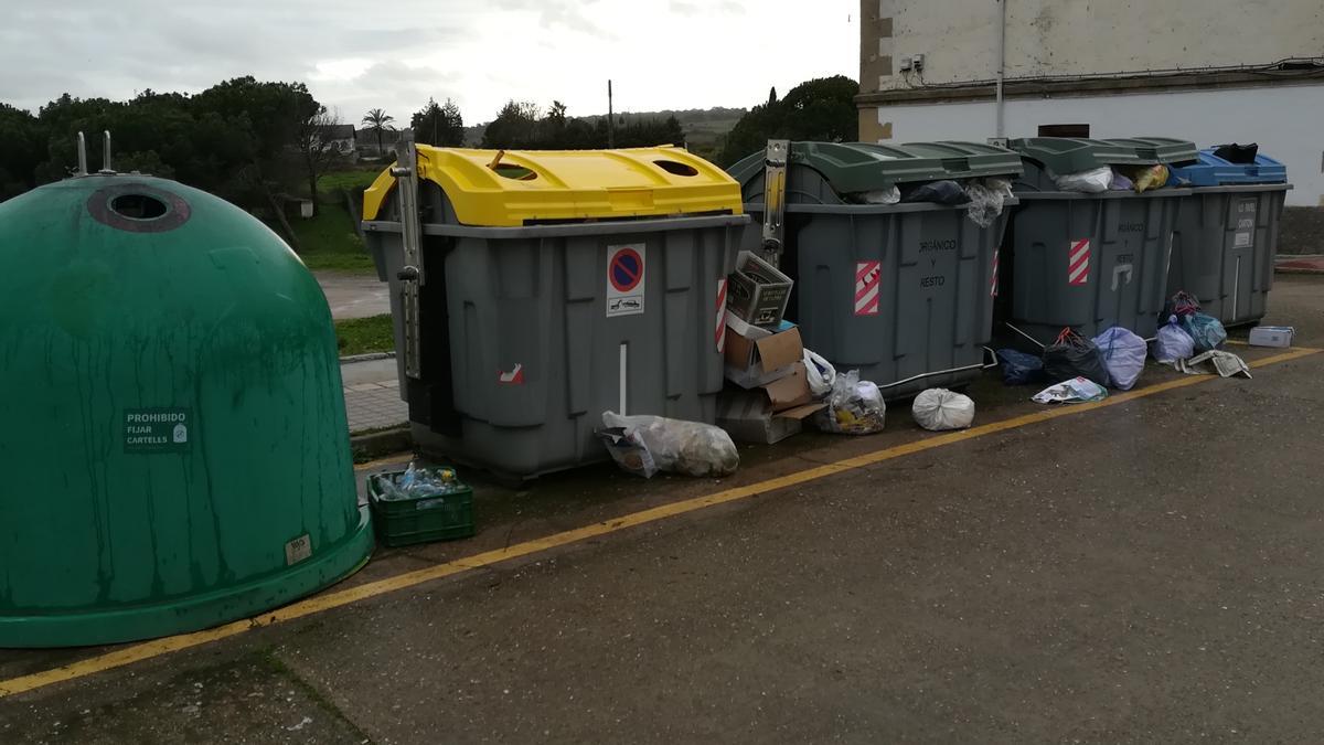 Contenedores con varias bolsas de basura alrededor, en una calle de Coria.