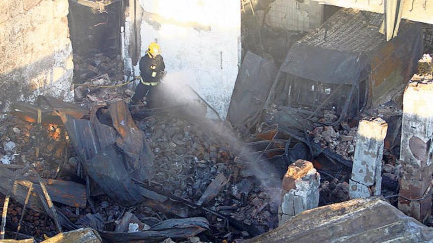 Los bomberos proseguían ayer con la refrigeración de la conservera calcinada en Cangas.  // C. Giménez