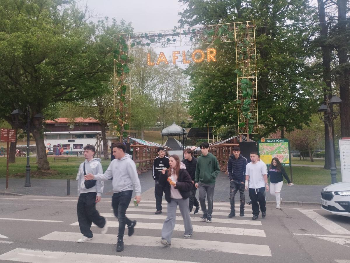 Un grupo de jóvenes cruza delante del arco de la Primera Flor instalado en el parque de Arriba.