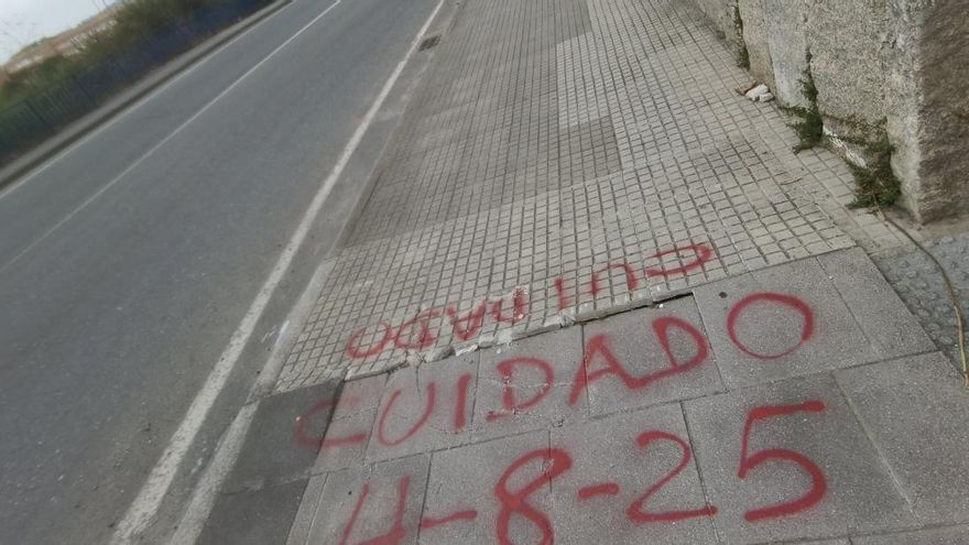 Una pintada avisa de una acera en mal estado en Eirís para evitar tropiezos
