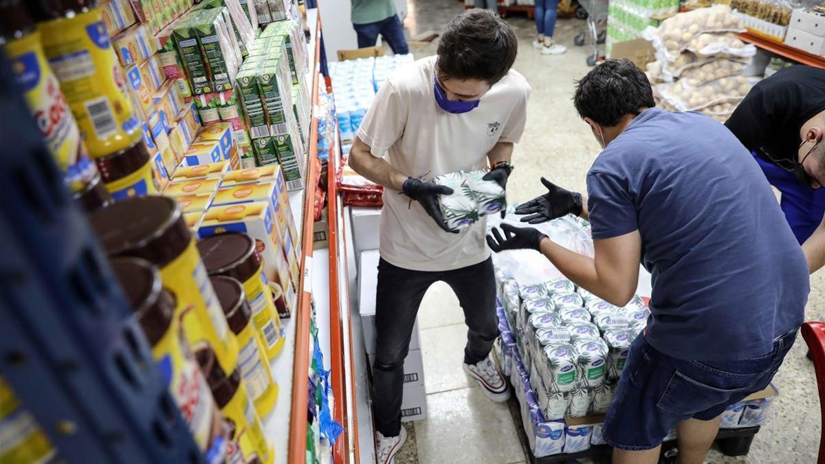 Voluntarios del economato interparroquial gestionado por Caritas en la ciudad de Torrent (Valencia) preparan alimentos para familias afectadas por el covid.