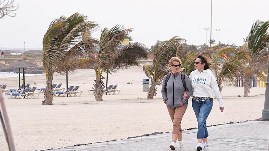 Archivo - Dos mujeres pasean por una playa de Fuerteventura con viento, a 27 de diciembre de 2022, en Fuerteventura, Las Palmas, Islas Canarias (España). El viento de hoy ha causado más de 125 incidentes, como caídas de ramas de árboles, palmeras, postes