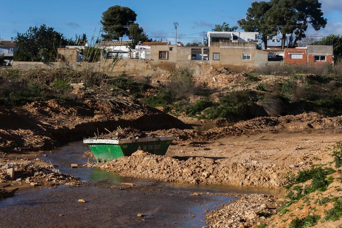 Un contenedor de obra dentro del barranco, con las casas pegadas a la ladera, al fondo.