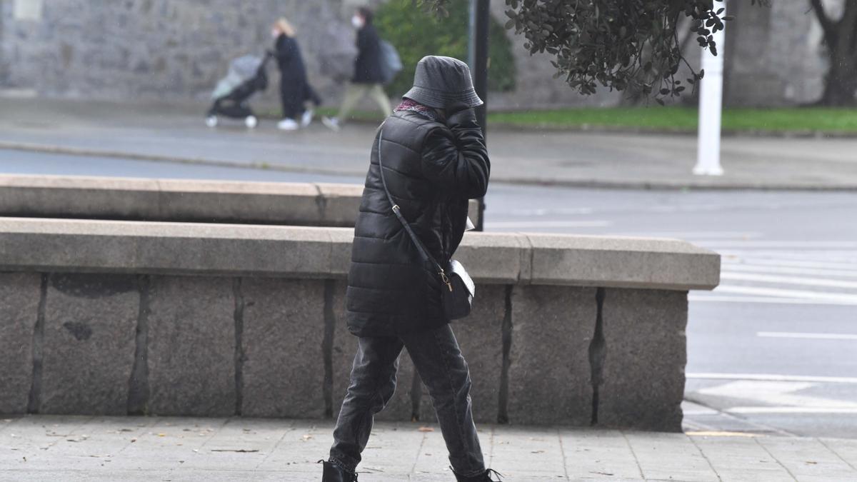 Una persona camina por A Coruña abrigada con un gorro.