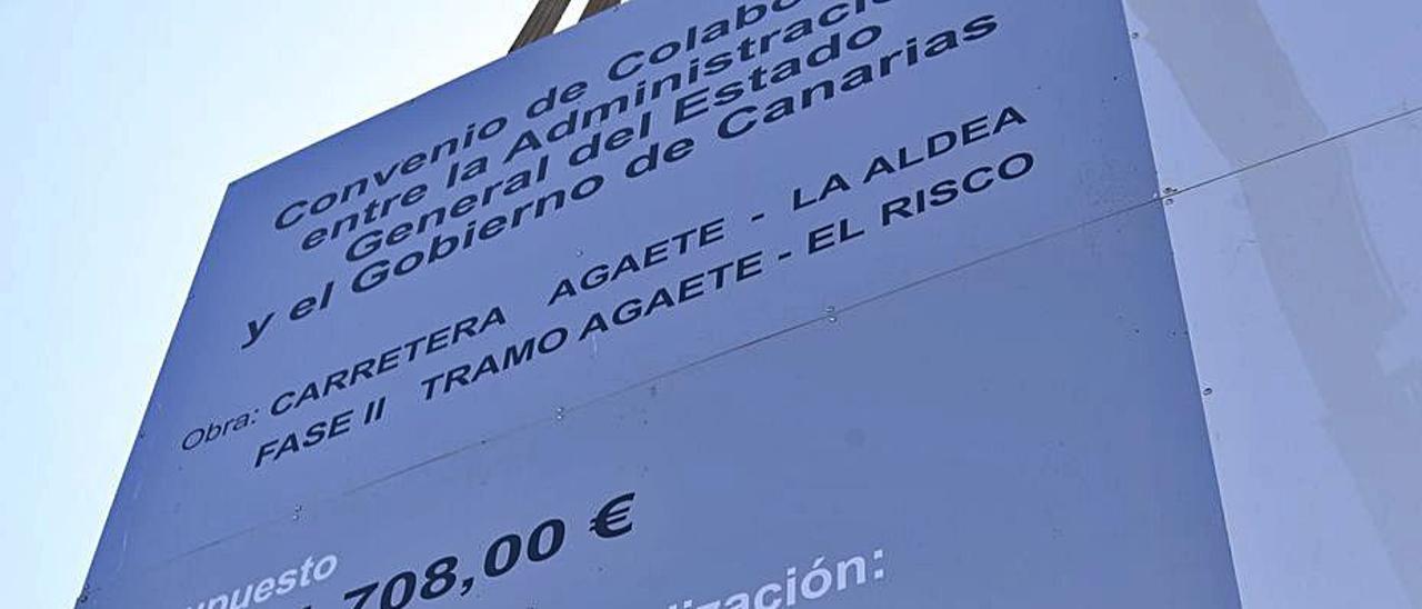 Un trabajador refuerza el cartel de las obras de la carretera de La Aldea.