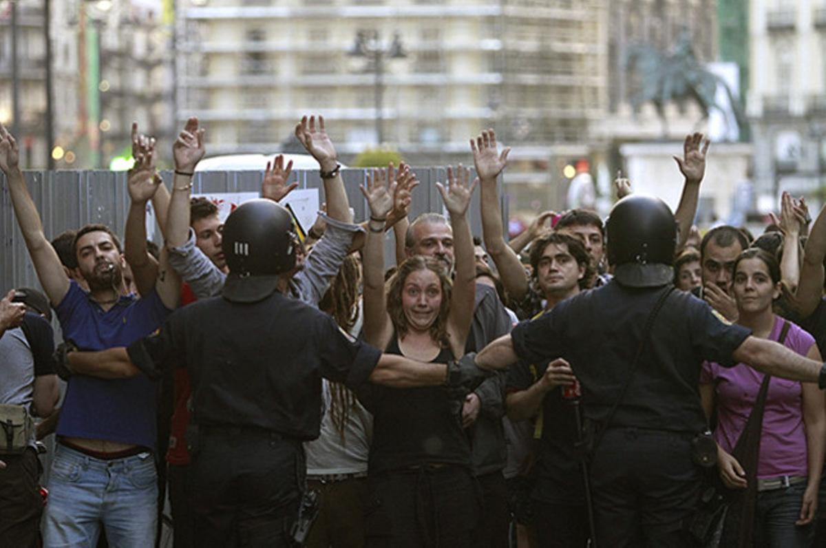 Dos agents de la policia, davant d’un grup d’’indignats’ que participen en una cassolada popular contra les retallades, a la madrilenya Puerta del Sol.