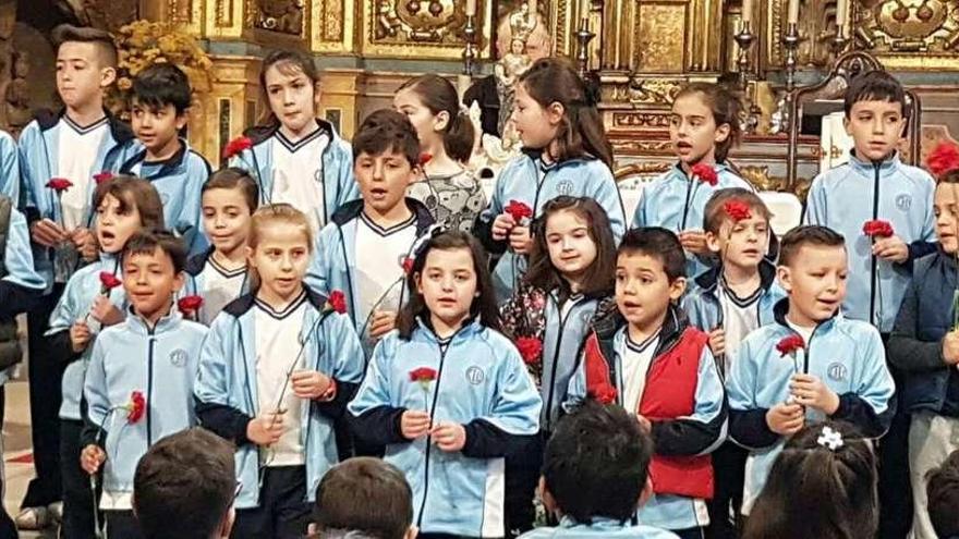 Un grupo de niños del colegio San Vicente de Paúl en la ofrenda a la Virgen que se observa detrás de ellos.