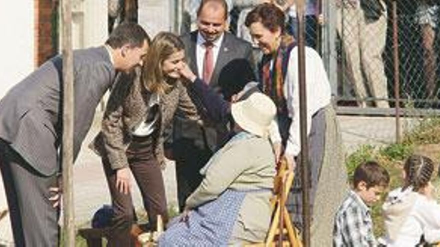 Los Príncipes saludan a Sabina Martínez y María Presentación Acebal, sentadas, durante la demostración del esfoyón del maíz.