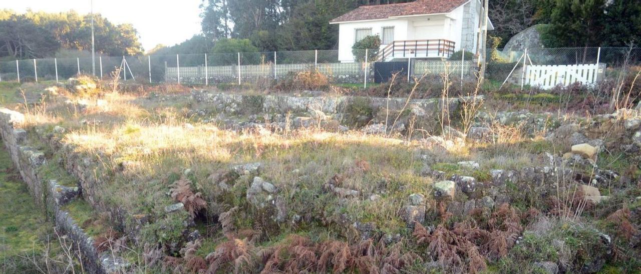 Estado actual del yacimiento de Adro Vello. Al fondo, la vivienda que habría que sortear para continuar las excavaciones. |   //  NOÉ PARGA