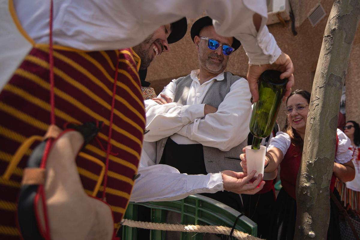 Una persona ofreciento vino en la Romería de Tegueste