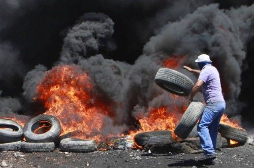 Un manifestante palestino quema neumáticos durante los enfrentamientos con el ejército israelí tras una protesta contra el asentamiento judío de Qadomem, en la aldea cisjordana de kofr Qadom, cerca de Nablus.