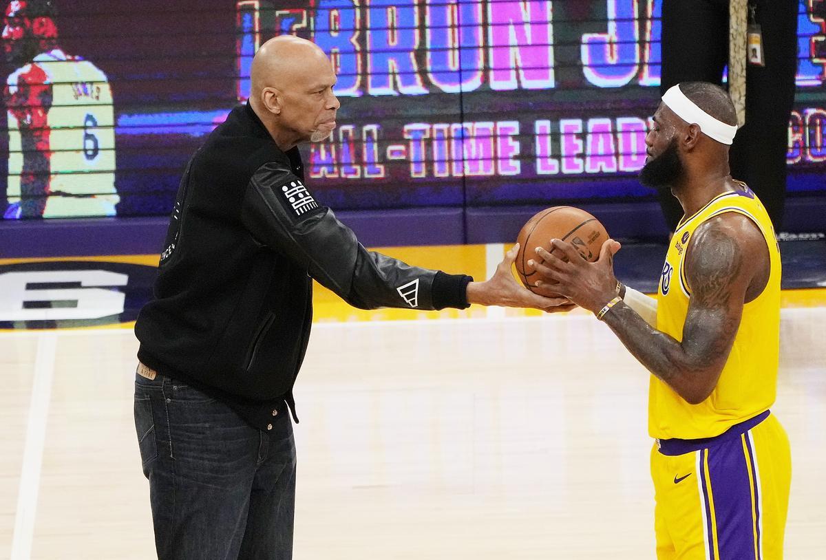 Kareem Abdul Jabbar le da el balón a LeBron James en signo de reconocimiento.