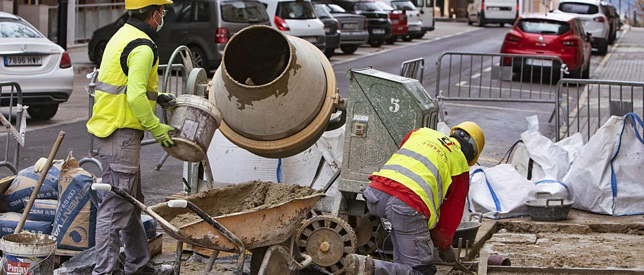 Dos operarios realizan trabajos de obra en una calle de Ontinyent, en una imagen de archivo | PERALES IBORRA