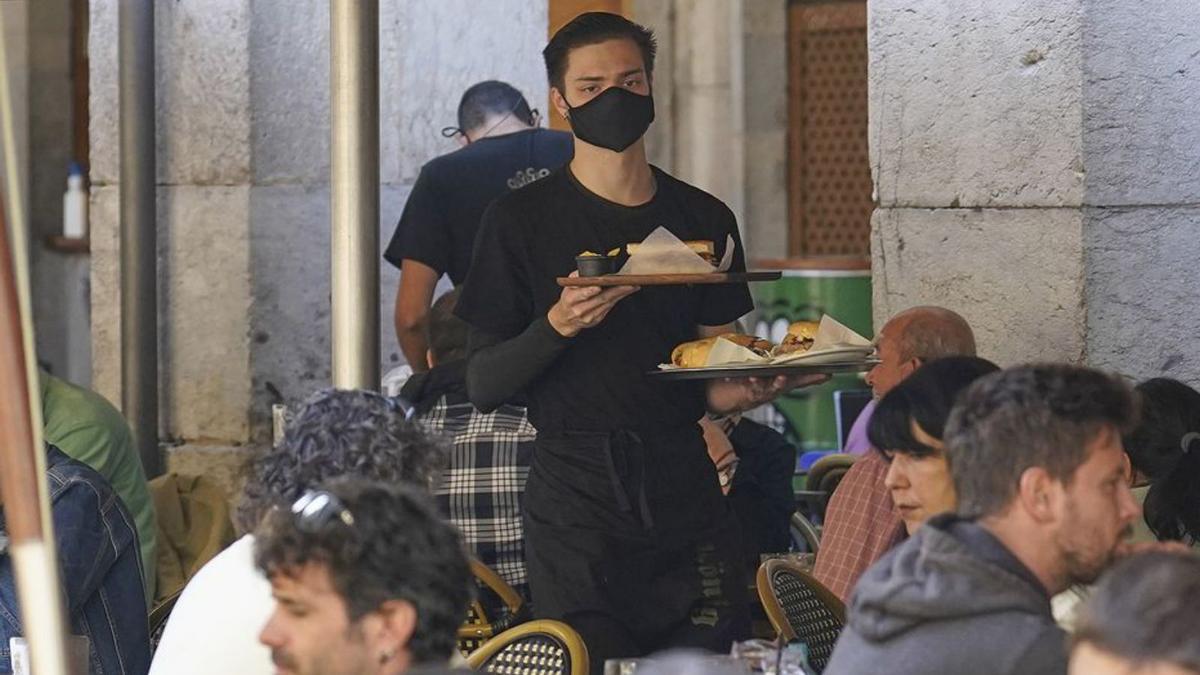 Un cambrer, servint una taula en una terrassa de Girona. | MARC MARTÍ