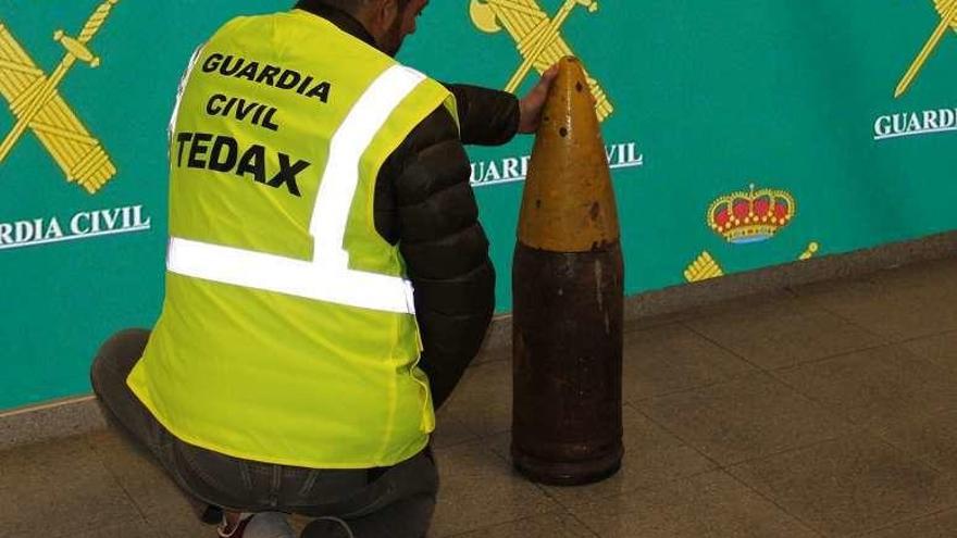 Un agente muestra el proyectil hallado en Ponteareas. // D.P.