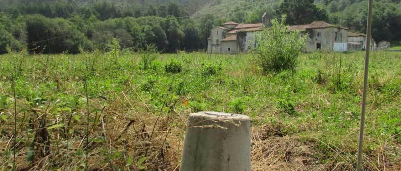 Uno de los mojones que separan el suelo público del particular, con la iglesia de Bedón al fondo.