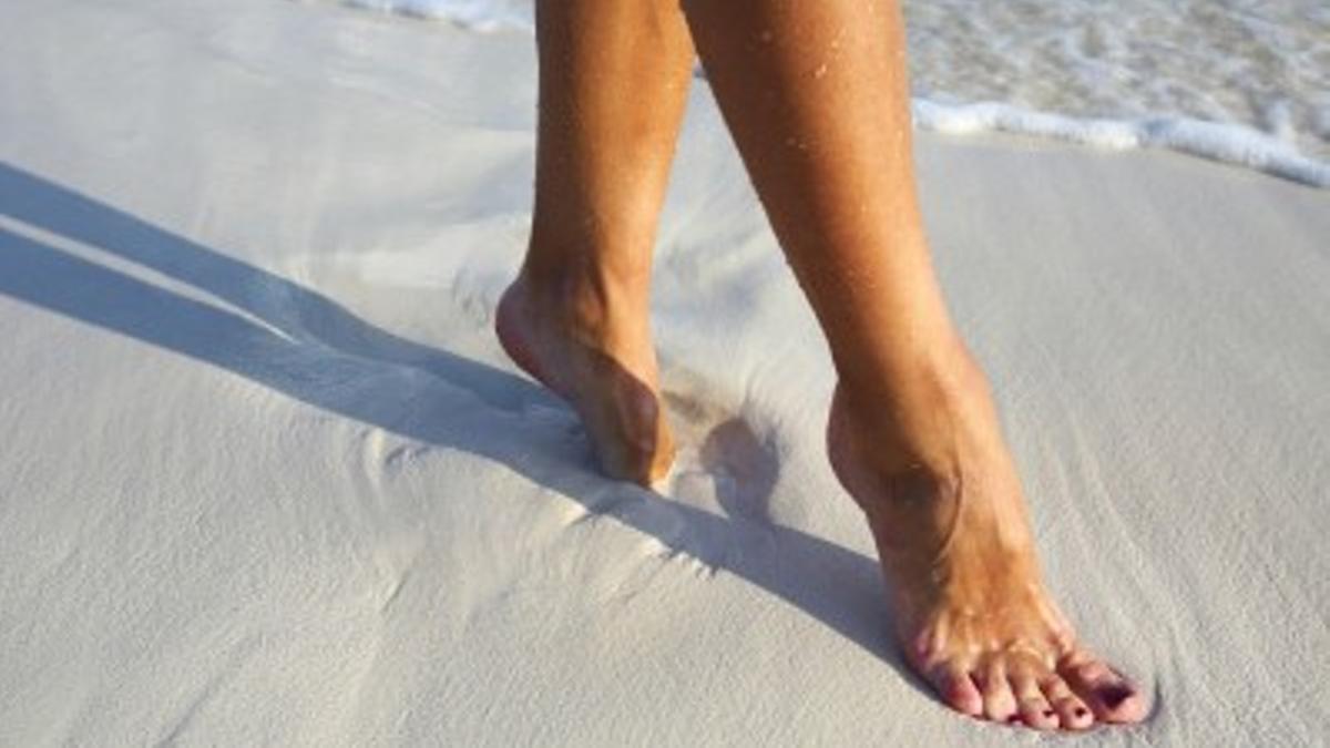Una persona camina descalza por la playa