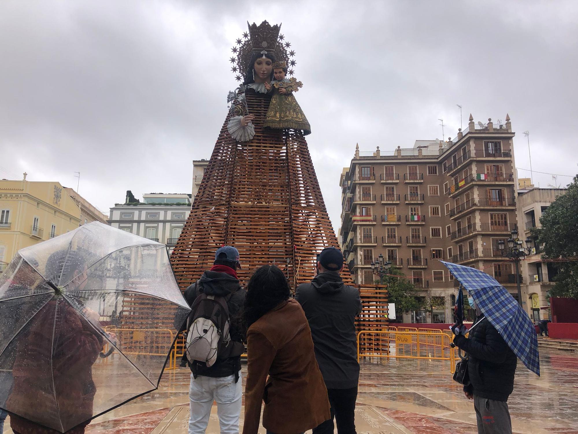 Paraguas sobre la imagen de la Virgen que espera la llegada de las flores