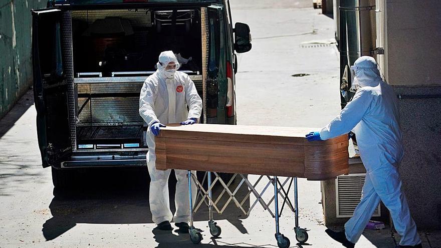 Dos trabajadores de una funeraria de Madrid trasladan el ataúd de una de las personas fallecidas por la covid en España.