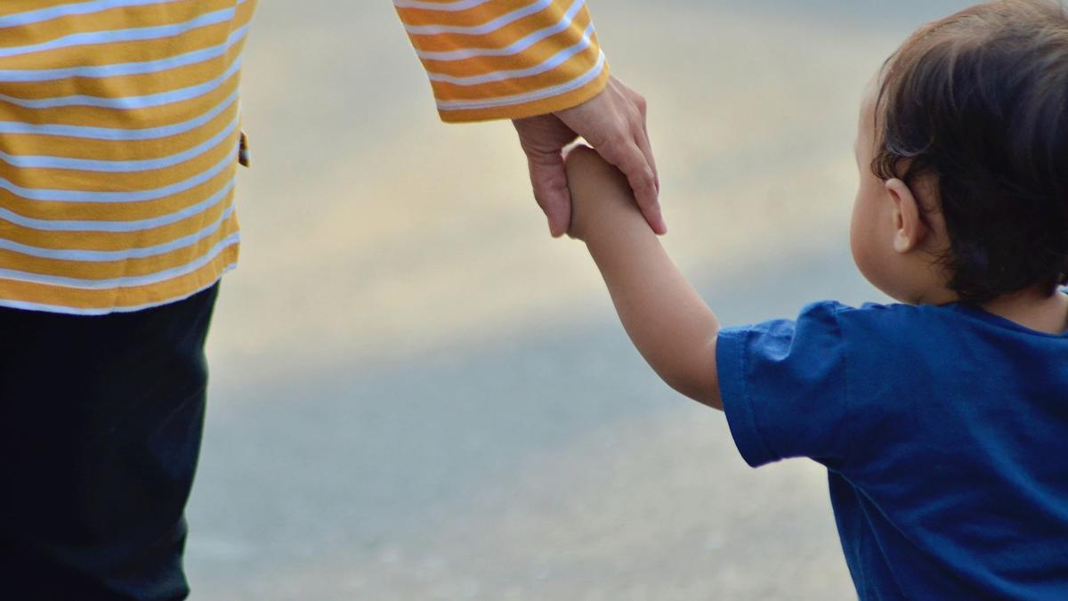 Una madre paseando con su hijo de la mano.