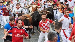 Varias personas corren delante de los toros en Pamplona.