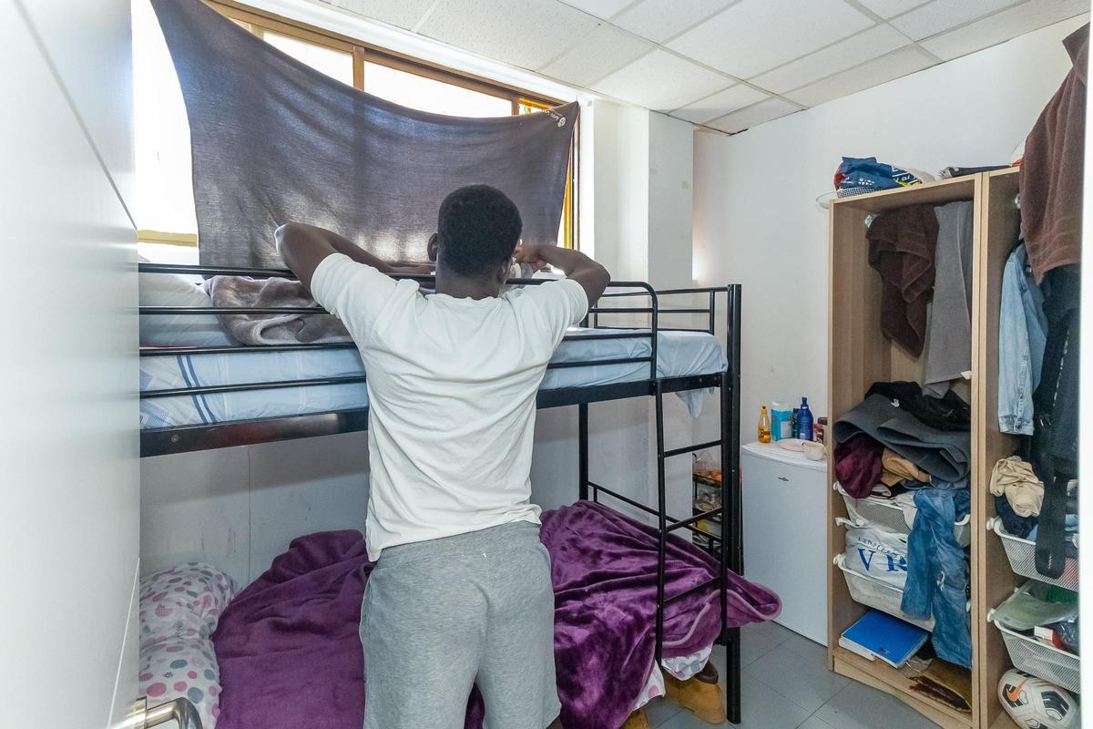 Amadou estira su cama en la habitación que comparte con otro chico en la pensión.