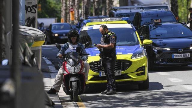 Un agent de la Guàrdia Urbana sanciona un motorista per haver circulat per un carril bus de Barcelona, al maig. | ZOWY VOETEN