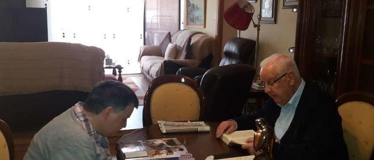 José Luis Sierra (dcha.) junto a su hija Susana leyendo en el salón de su casa de Lalín.