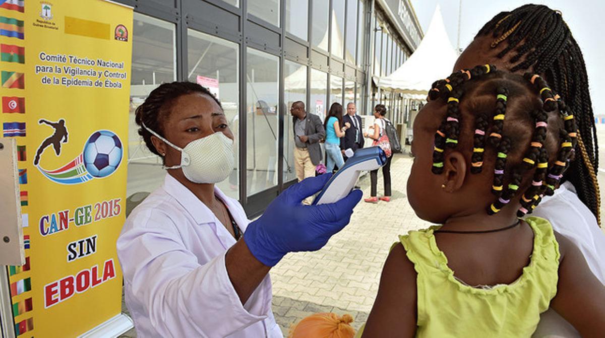 Una metgessa pren la temperatura a una dona i la seva filla, dijous, a l’aeroport de Bata (Guinea Equatorial).