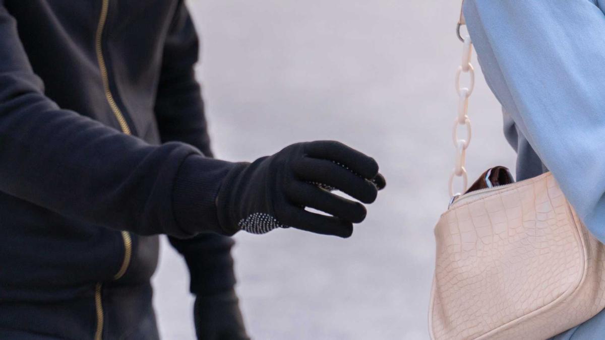 Un lladre intenta endur-se una cartera de l'interior d'una bossa de mà, en una imatge d'arxiu.