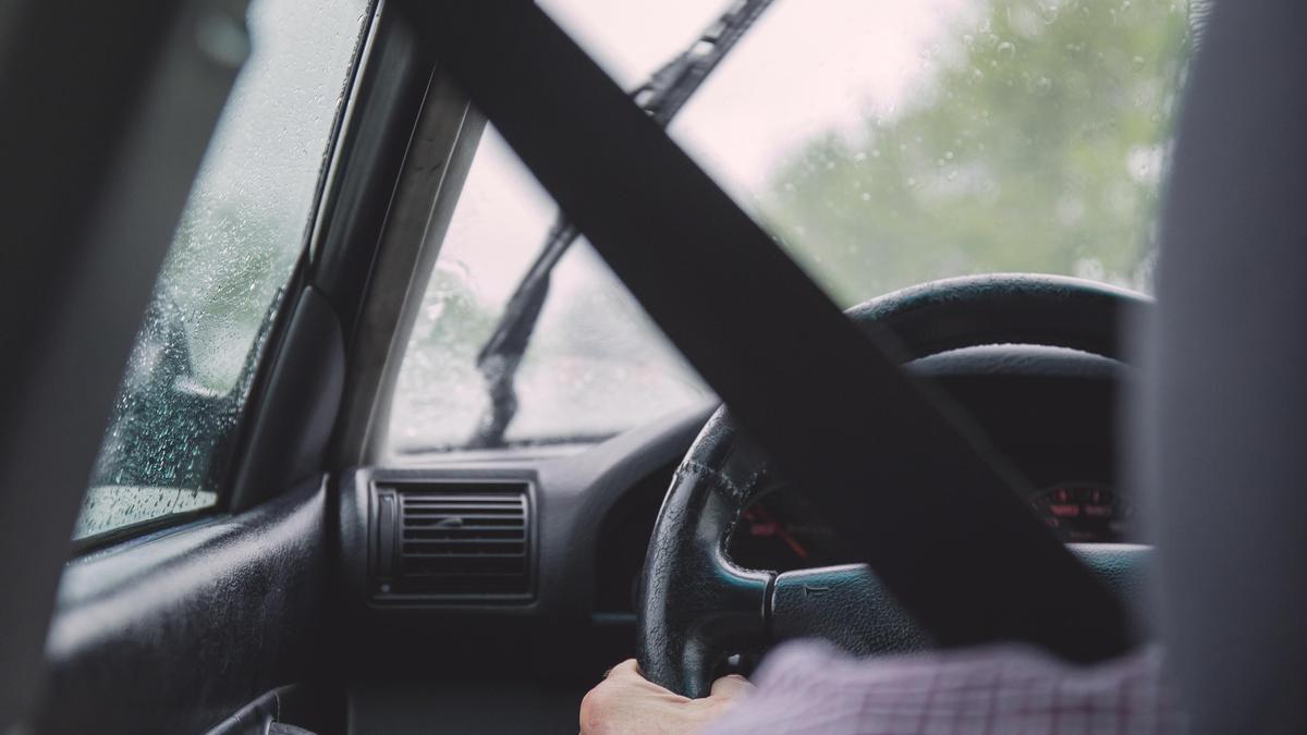 Un conductor dentro de un coche mientras llueve