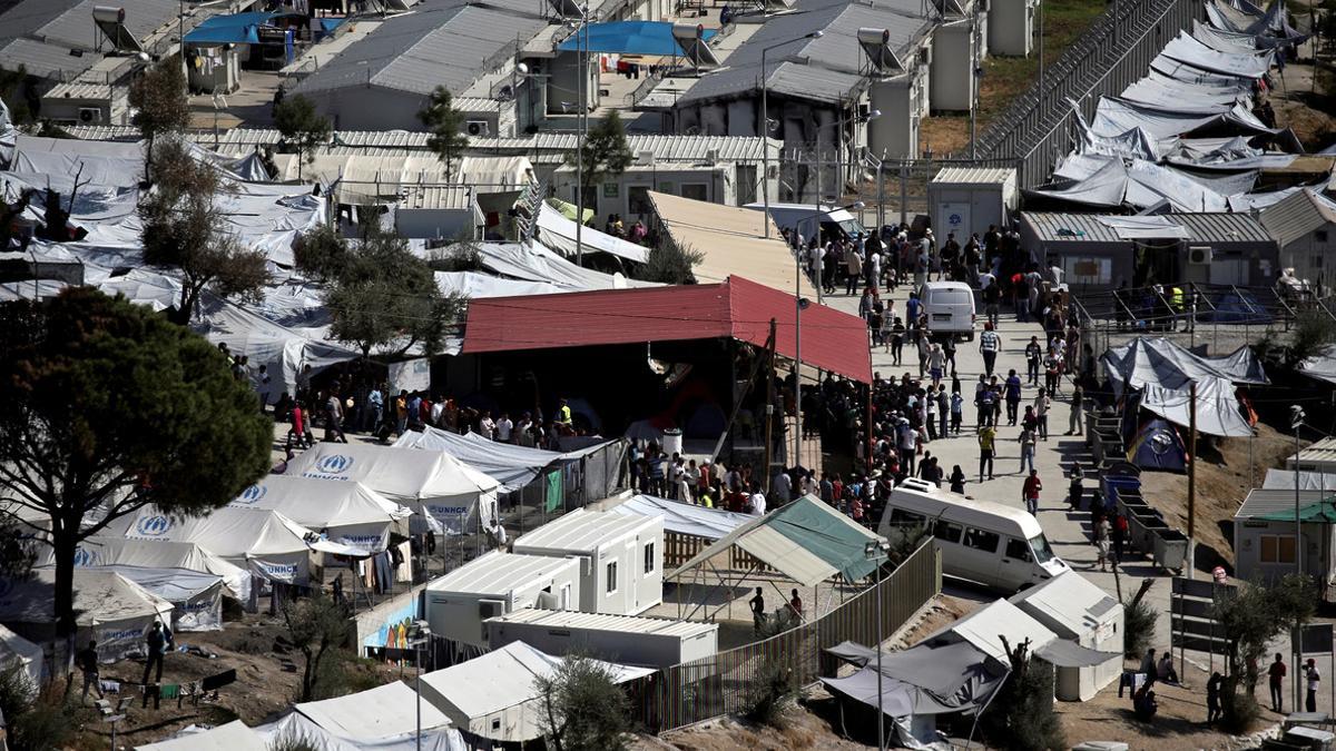 FILE PHOTO - Refugees and migrants line up for food distribution at the Moria migrant camp on the island of Lesbos