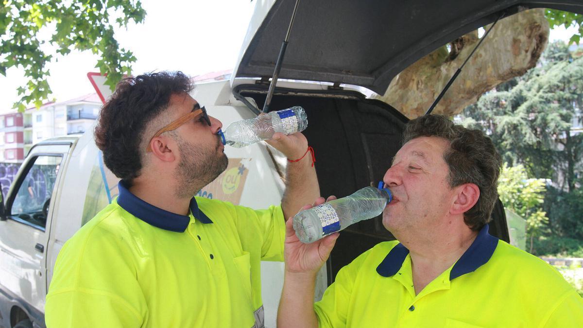 Dos trabajadores ourensanos beben agua durante su jornada laboral.