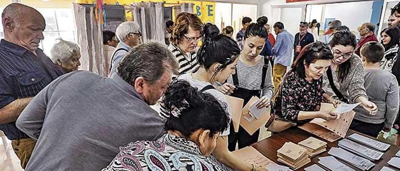 Varios ciudadanos escogen la papeleta antes de depositar su voto en la urna el pasado domingo en un colegio de Son Gotleu.