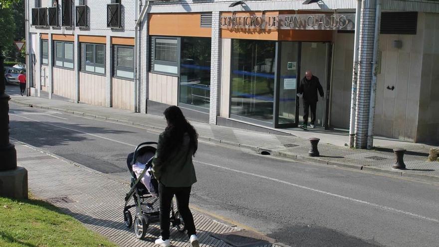 Una vecina con un niño recién nacido pasando por delante del consultorio de San Claudio, ayer.