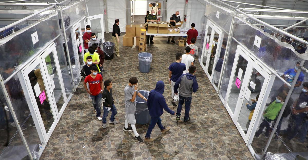 Fotografía del 17 de marzo cedida por la Oficina de Aduanas y Protección de Fronteras (CBP) donde se muestra a un grupo de niños haciendo cola para tomar alimentos en el centro de Donna, Texas.