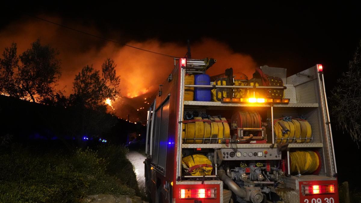 En primer terme, un camió de Bombers; al fons, l&#039;incendi forestal de Roses